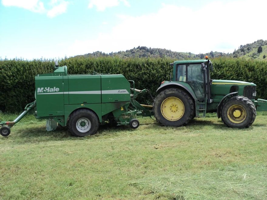 Green McHale baler hitched to a John Deere tractor on short grass